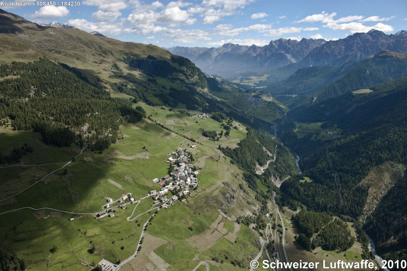 Guarda im Unterengadin, Trägerin des Wakkerpreises 1975 (Position: 2'807'196.40, 1'184'097.73). Im Bildzentrum: Guarda; kleine Siedlung zum Bildhintergrund hin: Bos-Cha; im Talgrund vorne im Bild: Bahnstation RhB; talabwärts zum Bildhintergrund hin Richtung Ftan und Scuol.